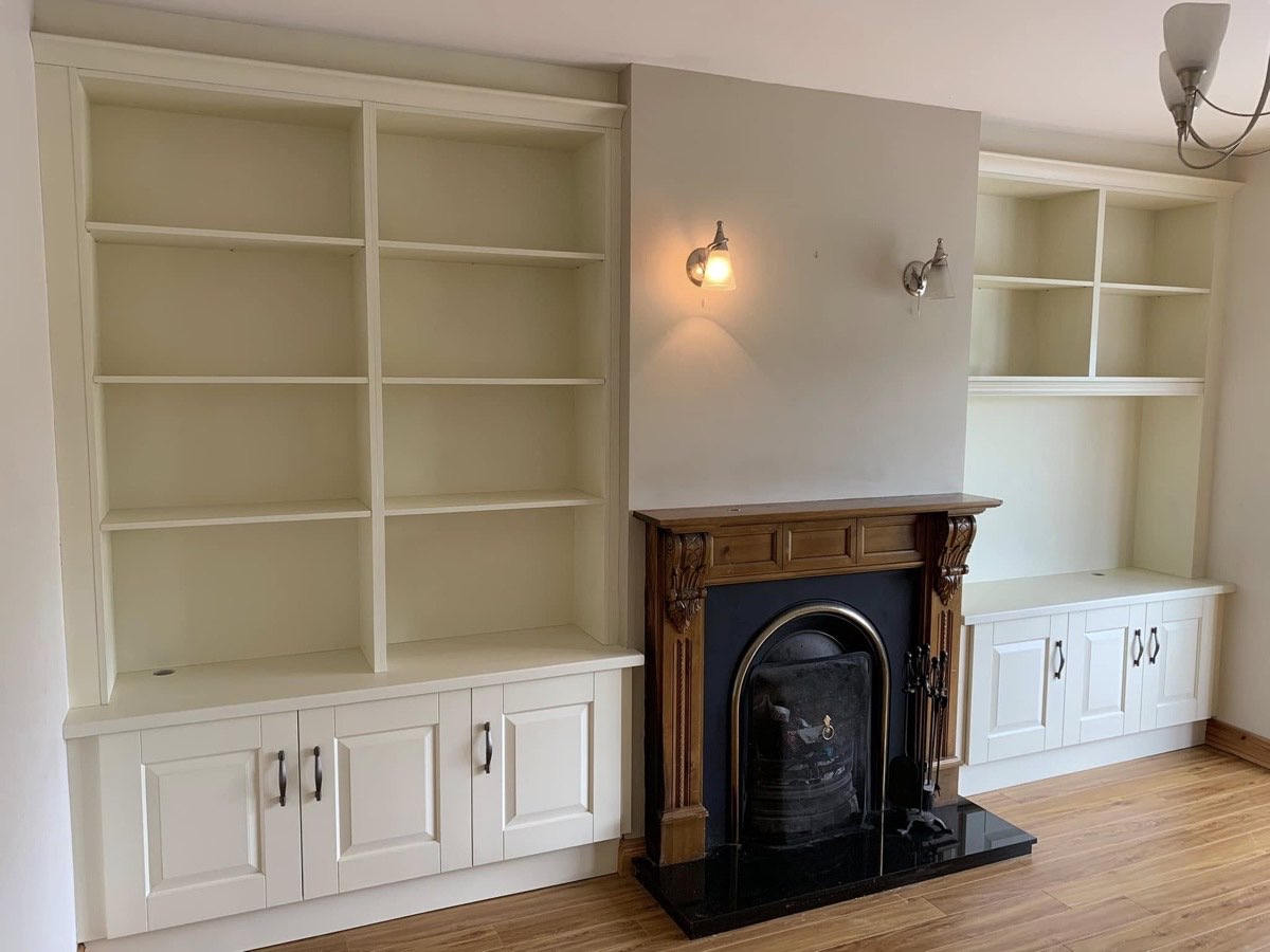 Painted alcove shelving over cupboards, built either side of a cast iron fireplace.