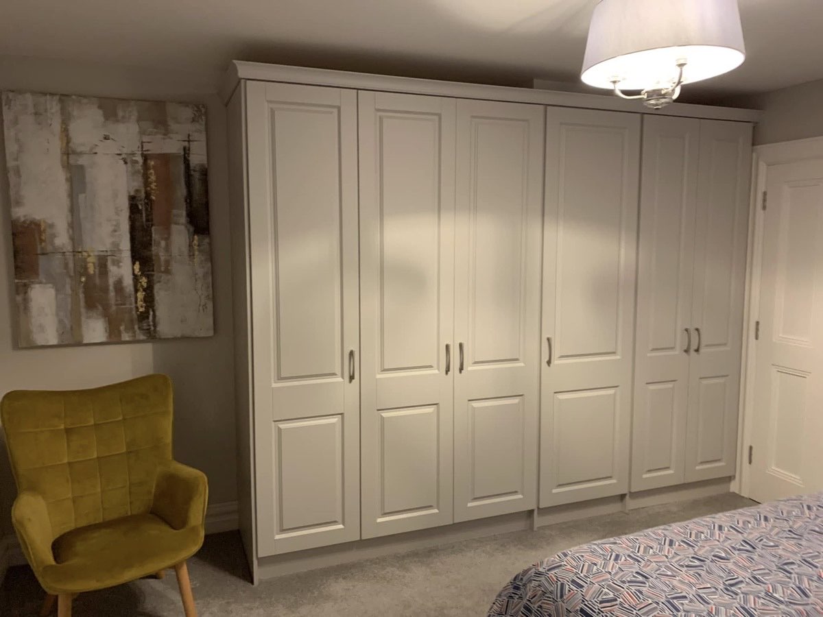 A run of cream painted fitted wardrobes along a bedroom wall.